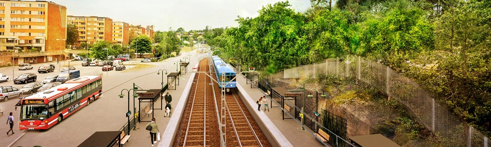 Vy över Fisksätra station, järnvägsspår och perrong samt hus och vägar.