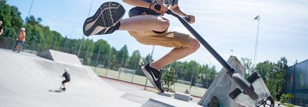 Någon hoppar med sin kickbike i en skateramp. I bakgrunden åker några på kickbikes.