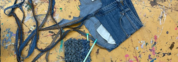 Trasiga jeans som ligger på en bänk tillsammans med en påbörjad stickning.