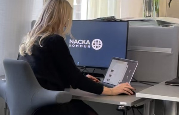 Foto i kontorsmiljö på en person bakifrån, som sitter och arbetar vid sin dator och skärm