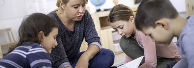 Bilden visar barn som läser tillsammans med en vuxen.