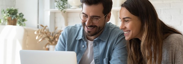 En man och en kvinna skrattar och tittar tillsammans på en skärm