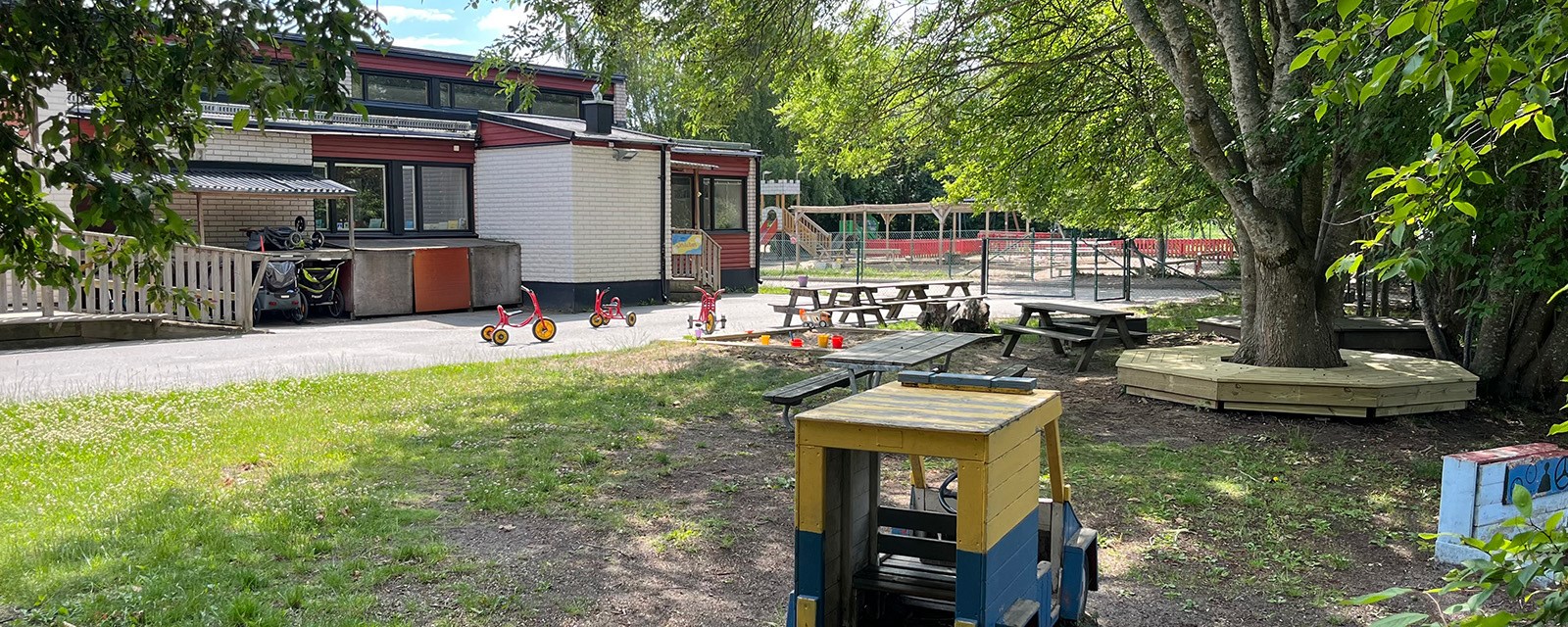Förskola med vitt tegel med blå träbil i förgrunden.